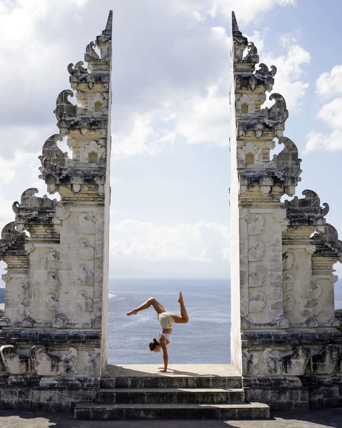 A handstand framed by the split temple gate above the ocean